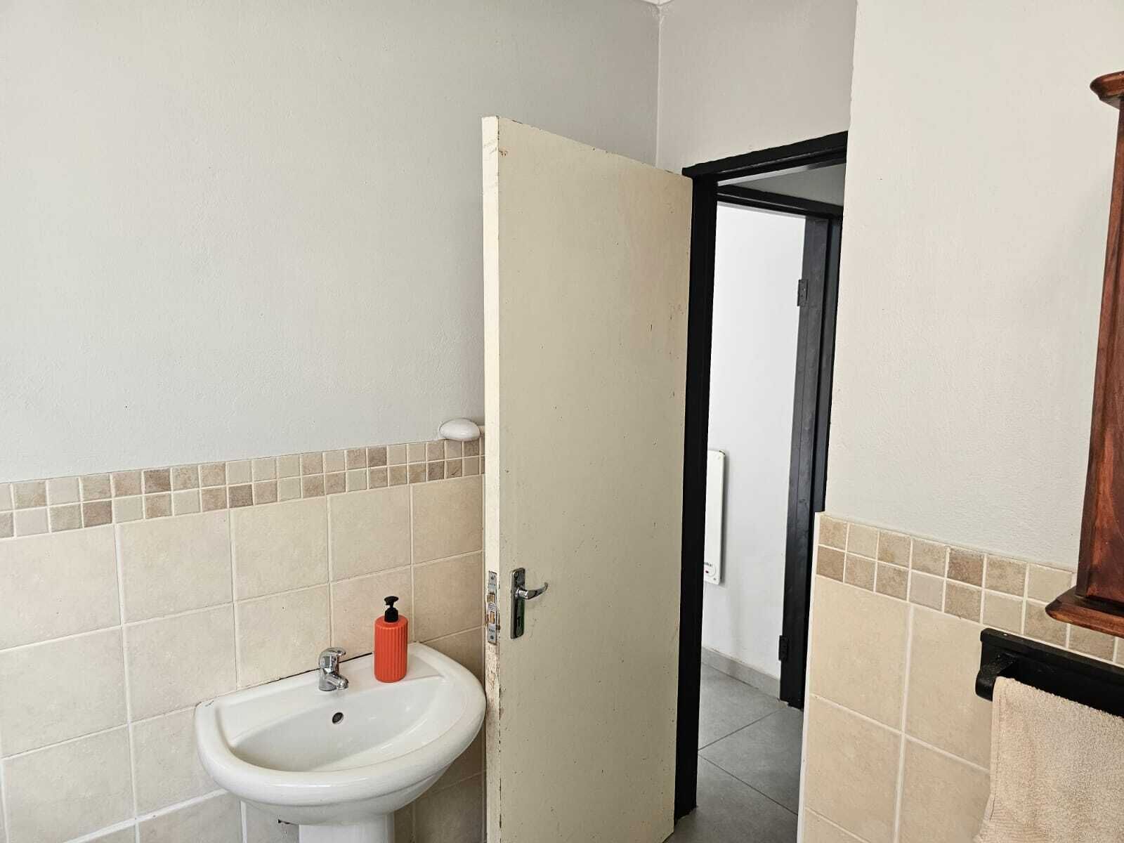 A bathroom with a white sink, a soap dispenser, and a towel rack.