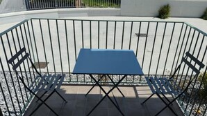 A blue table and two chairs set up on a tiled patio with a metal fence. - Lotelito Apartment (Fisciano)