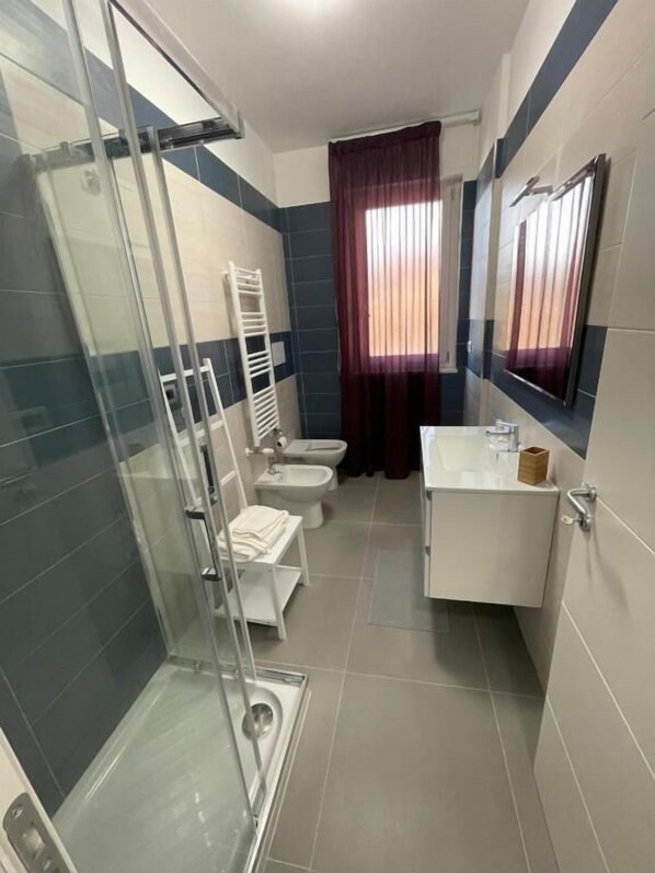 A bathroom with a glass shower enclosure, a toilet, a bidet, and a sink with a mirror. - Lotelito Apartment (Fisciano)