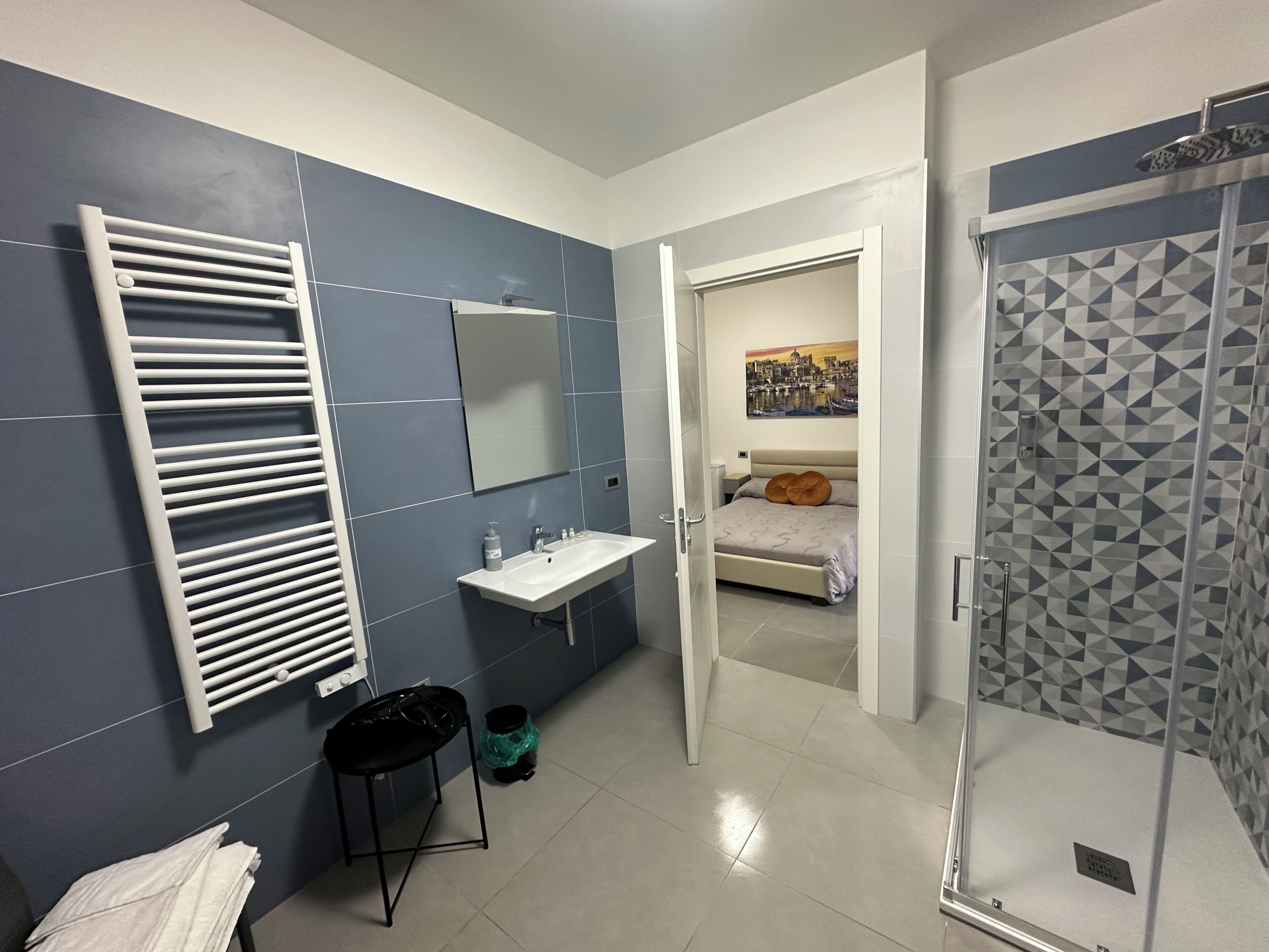 A modern bathroom with a towel rack, sink, and shower.