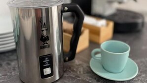A stainless steel electric kettle with a black handle and a digital control panel, placed on a marble countertop next to a teal cup and saucer. - Lotelito Apartment (Fisciano)