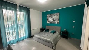 A bedroom with a bed, a nightstand, a window with curtains, and a wall-mounted picture. - Lotelito Apartment (Fisciano)