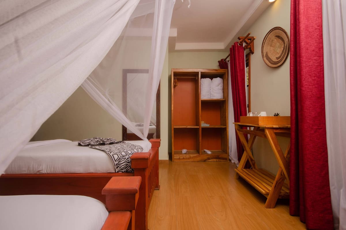 A bedroom with a canopy bed, a wooden wardrobe, and a mirror.