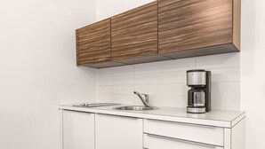 A modern kitchen with white cabinetry, a stainless steel sink, and a coffee maker. - Geräumiges 39 m² Apartment für 2–3 Personen (Alpenresidenz (Bad Gastein))