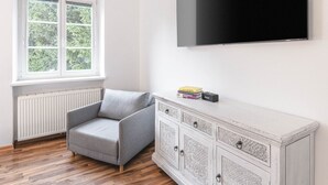 A modern living room with a grey sofa, a white cabinet, and a mounted TV. - Geräumiges 39 m² Apartment für 2–3 Personen (Alpenresidenz (Bad Gastein))