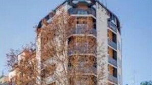 Ein mehrstöckiges Gebäude mit Balkonen, einem Eingang im Erdgeschoss und einem sichtbaren Schaufenster.