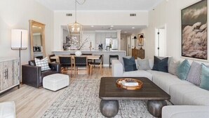A modern living room with a sofa, coffee table, and dining area. - Sterling Beach 1202 Luxury Beachfront, Heated Pool, Walk in Shower, FREE Golf (Panama City Beach)