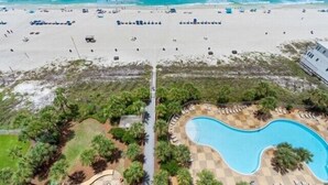 An aerial view of a beach resort with a swimming pool, beach chairs, and umbrellas. - Sterling Beach 1202 Luxury Beachfront, Heated Pool, Walk in Shower, FREE Golf (Panama City Beach)