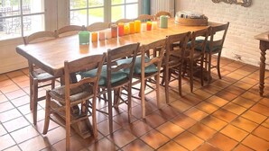 Een eetruimte met een houten tafel en stoelen, een raam met gordijnen en een hanglamp.