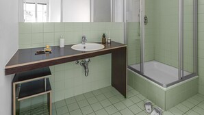 Een badkamer met een wastafel, spiegel en douche.