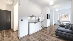 Een moderne keuken met witte kastjes, een inbouwoven en een flatscreen televisie.
