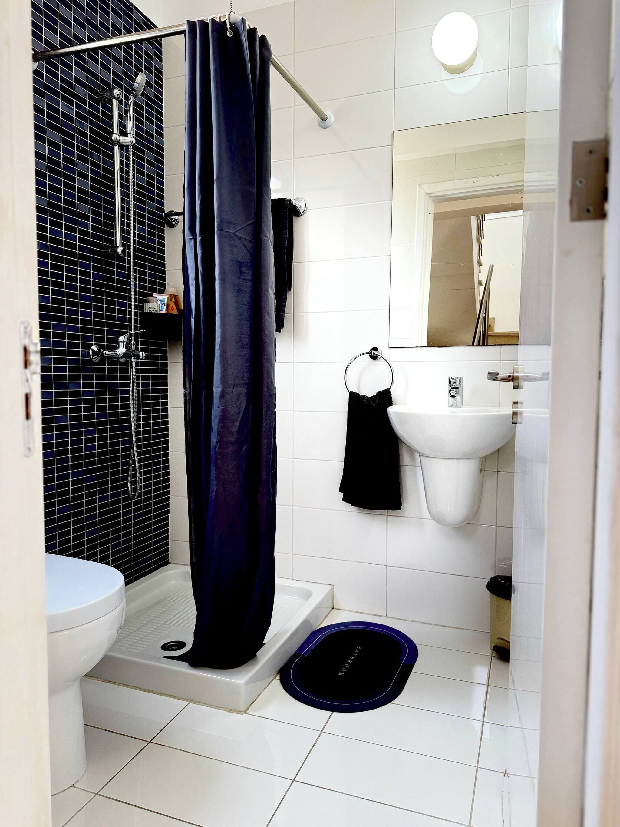 Un baño con ducha, inodoro, lavabo y espejo.