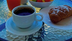 A table with a drink, a bowl of fruit, a pastry, and a cup of coffee, overlooking a pool and the sea. - Amáni Seaview 3 Bedrooms Luxury Villa (Pegeia)
