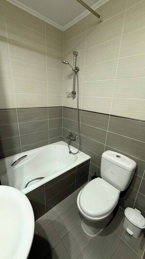 A modern bathroom with a bathtub, toilet, and sink. - Aphrodite Gardens Modern Apartment (Paphos)