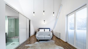 Ein modernes Schlafzimmer mit einem großen Bett, einer Glasdusche und Blick ins Freie.