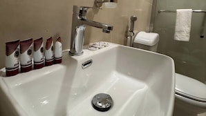 A bathroom with a large white sink, a mirror, a glass shower enclosure, and a toilet. - KANON Hotel Makkah  (Makkah)