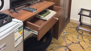 A wooden desk with a computer, a remote control, and a book. - KANON Hotel Makkah  (Makkah)