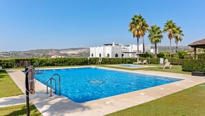 Una piscina con un flotador salvavidas, palmeras y un edificio al fondo.