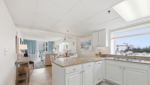 Una cocina moderna con armarios blancos, una isla grande y vistas del vecindario.