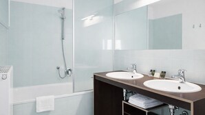 Un baño moderno con dos lavamanos, cabina de ducha de vidrio y un espejo grande.