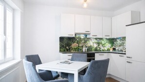 Una cocina moderna con armarios blancos, una mesa de comedor blanca y sillas azules.