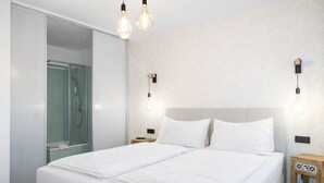 A modern hotel room with a large bed, a walk-in shower, and wall-mounted light fixtures. - 2-Schlafzimmer-Apartment mit Bergblick für 4–6 Personen (Alpenresidenz (Bad Gastein))