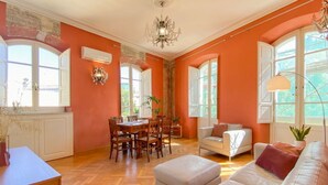 Una habitación con una mesa de comedor, sillas, un sofá y una araña.