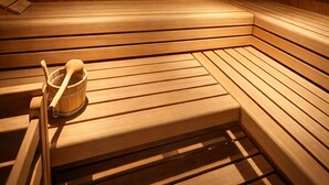 A sauna with wooden benches and a wooden bucket with a wooden spoon. - Deluxe Apartment mit 57 m² für 2–4 Personen (Alpenresidenz (Bad Gastein))