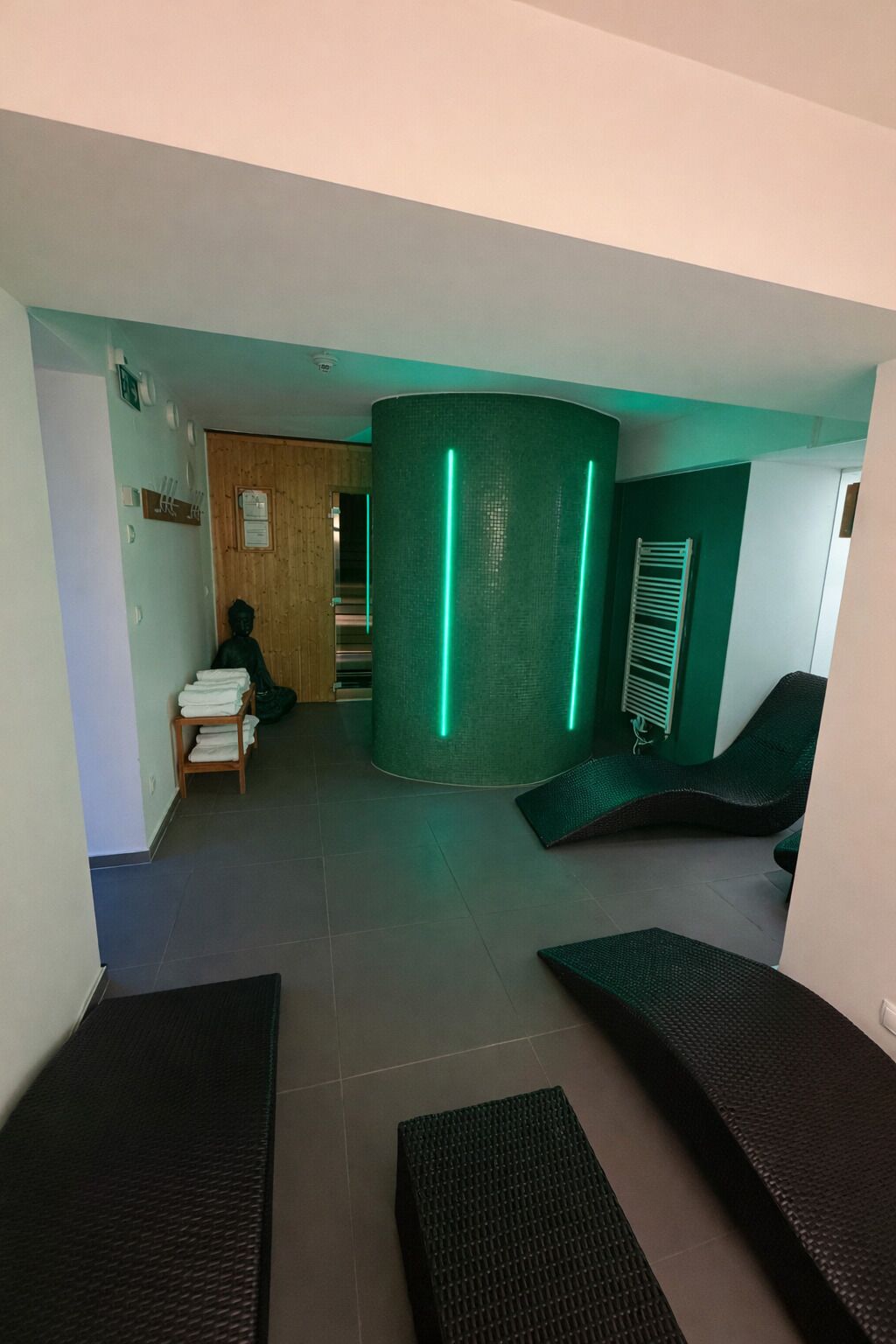 Un hall d’entrée moderne avec un mur vert incurvé, un comptoir d’accueil et des espaces de détente.