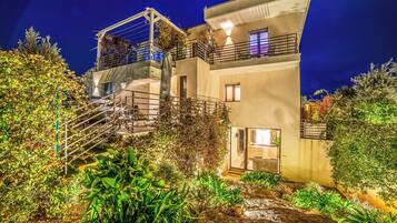 Un edificio moderno di due piani con un balcone, una scala e un’area giardino.