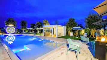 Una piscina con sedie a sdraio e un elemento decorativo a fuoco.
