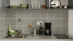Une cuisine moderne avec des meubles gris, un pare-feu décoré et un lave-vaisselle encastré.
