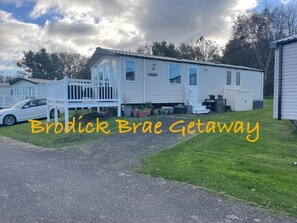 A mobile home with a porch and a car parked in front. - Brodick Brae Getaway (Ayr)