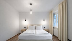 Un dormitorio moderno con una cama grande, dos mesitas de noche y una ventana con cortinas.