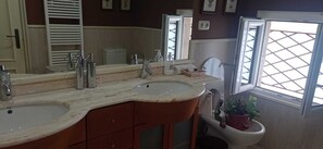 A bathroom with two sinks, a large mirror, and a window with a lattice design. - Cabanas, Casa Unica, on the beachfront (Cabañas)