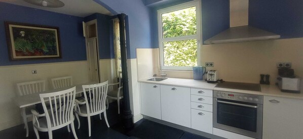 A compact kitchen with white cabinets, a built-in oven, and a window with a view of greenery. - Cabanas, Casa Unica, on the beachfront (Cabañas)
