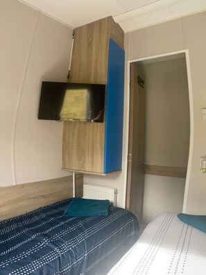 Une chambre à coucher avec un lit, un téléviseur fixé au mur et une porte.