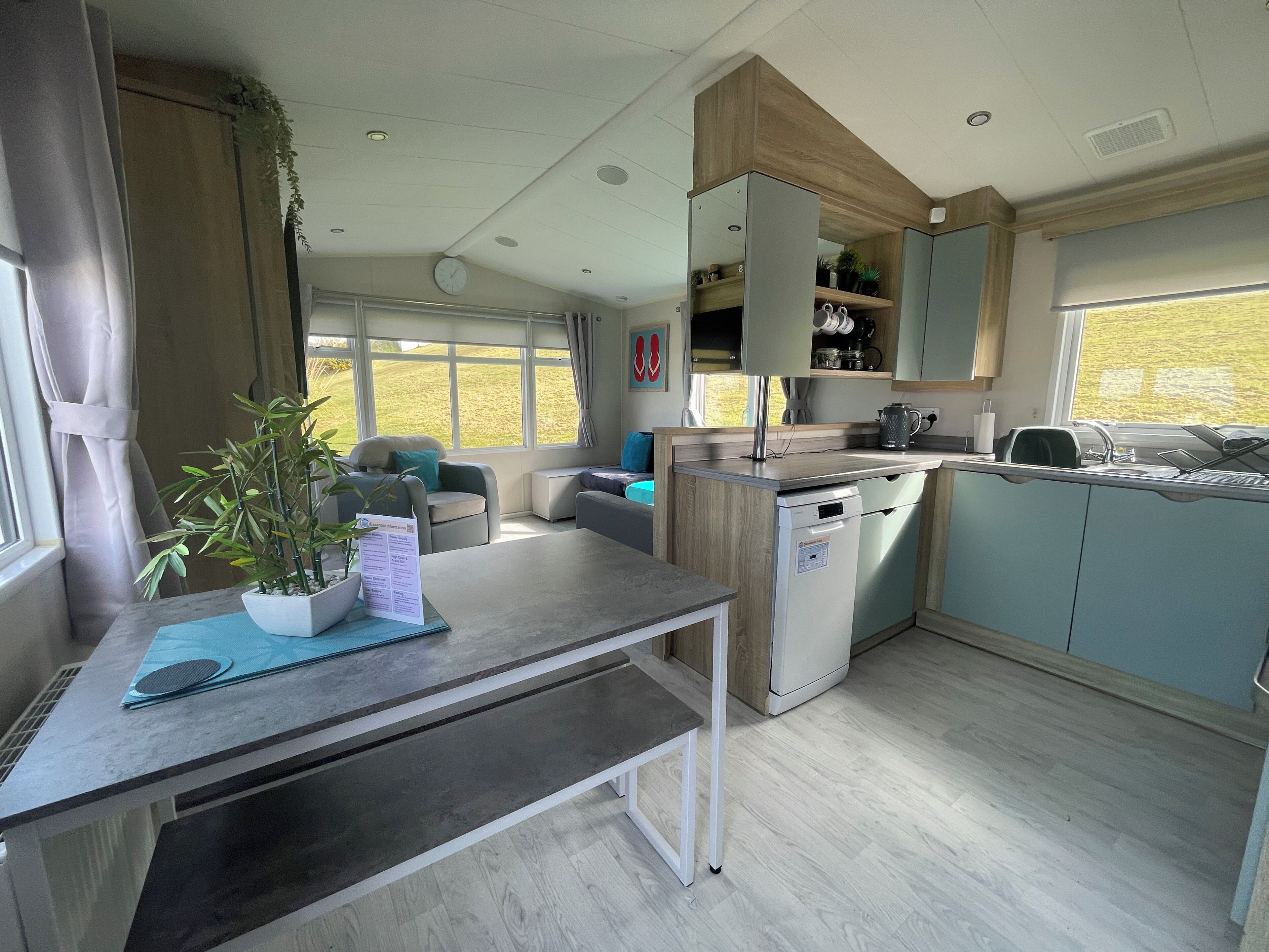 Cocina compacta con lavavajillas, fregadero y ventana con vistas a una zona verde.