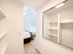 Une chambre à coucher moderne et minimaliste, dotée d’un grand miroir, d’un lit et offrant une vue sur l’extérieur.