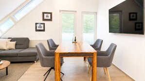 Un salon moderne avec une table à manger en bois, des canapés gris et une grande fenêtre.