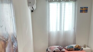 Ein Schlafzimmer mit Bett, Nachttisch, Lampe, einem Fenster mit Vorhängen und einer Tür mit einem einzigartigen Design.