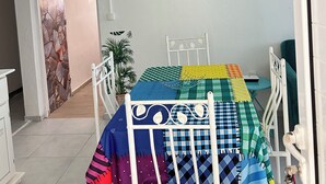Ein Schlafzimmer mit einem Bett, einem Schreibtisch, einem Stuhl, einer Zimmerpflanze und einem Bild an der Wand.