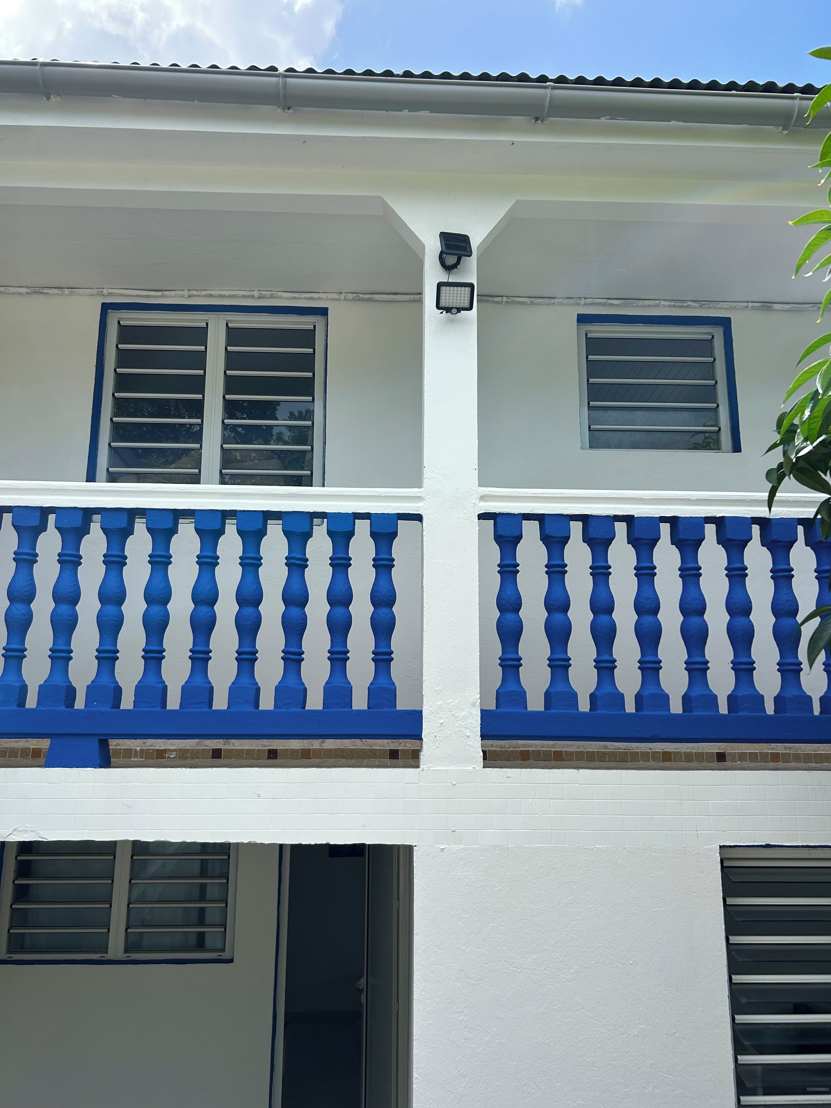 A building with a white exterior, blue window frames, and a blue balcony railing.