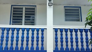 Ein Gebäude mit weißer Fassade, blauen Fensterrahmen und einem blauen Balkongeländer.