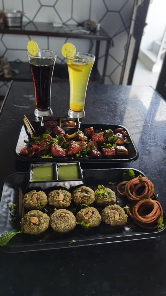 A table with food and drinks, including skewers, falafel, and two glasses of beverages.