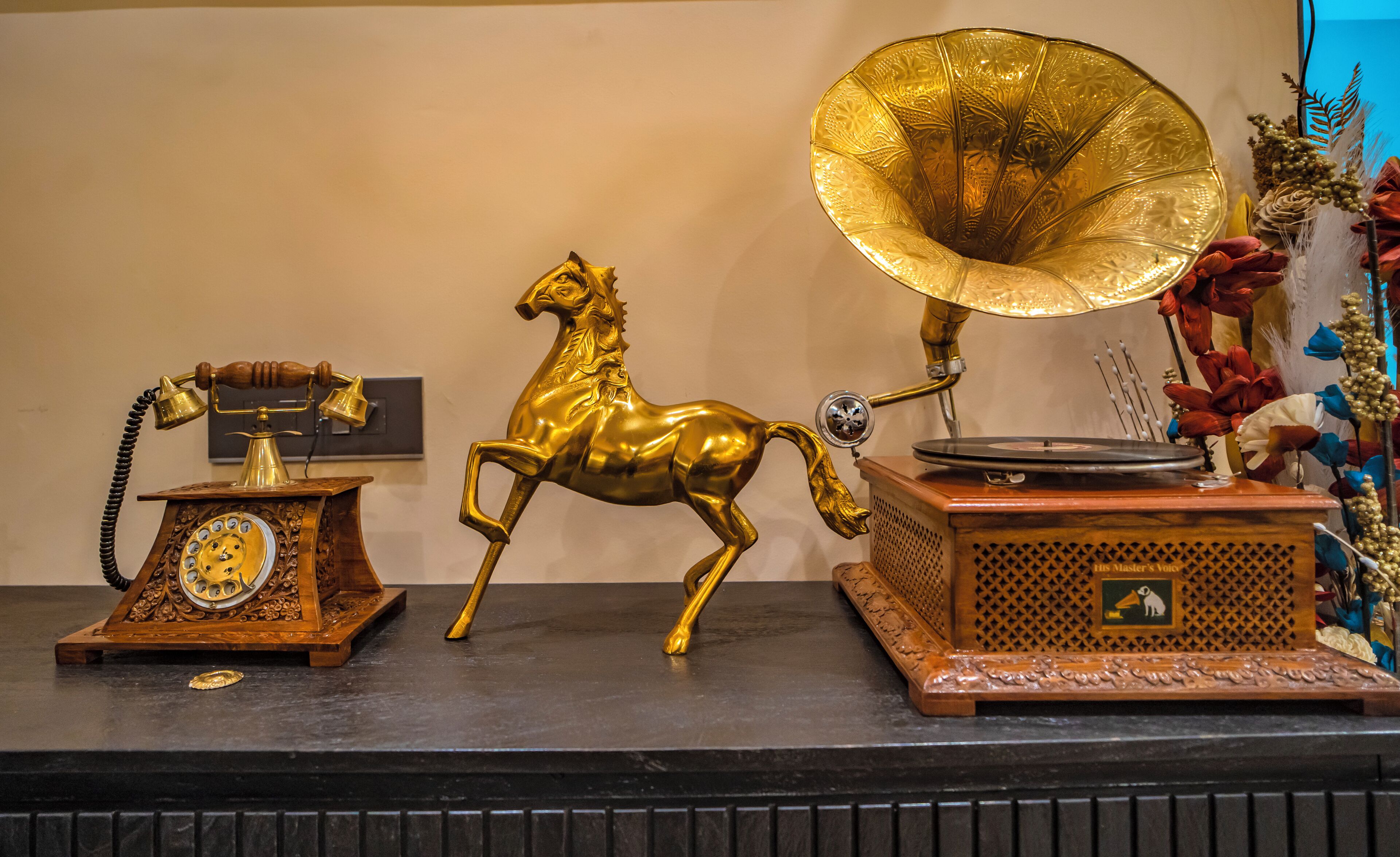 A vintage radio with a horse figurine and a phonograph on a wooden table.
