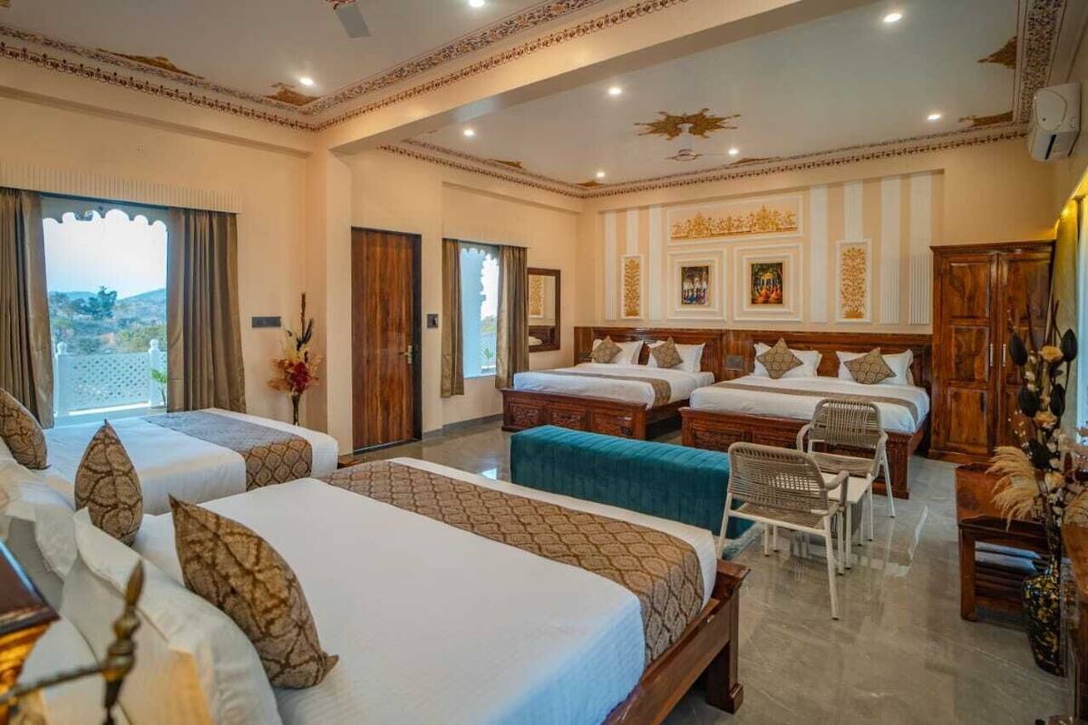 A hotel room with two beds, a sitting area with chairs, and a view of the outdoors.