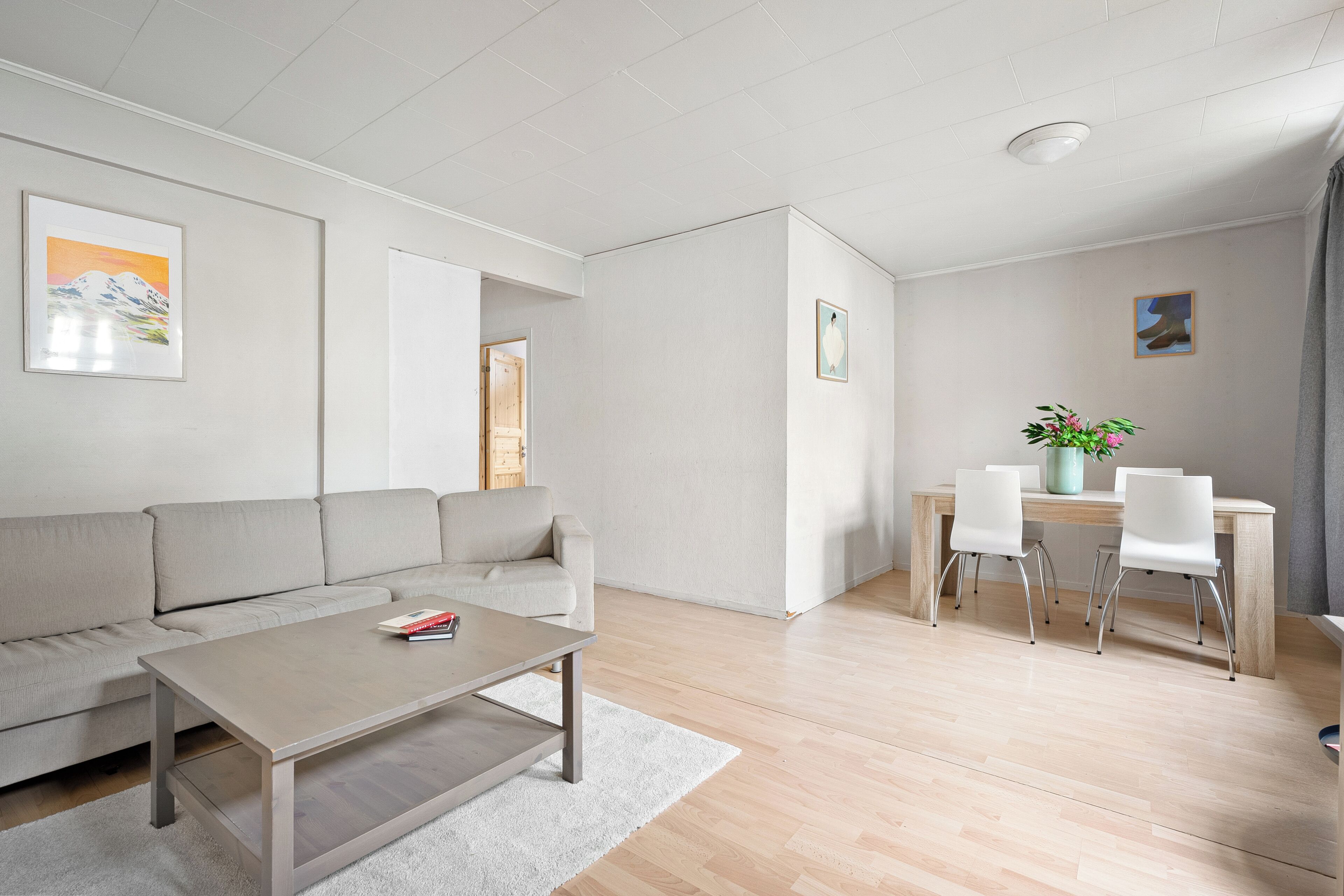 Uma sala de estar moderna com sofá, mesa de centro e área de jantar com cadeiras e mesa.