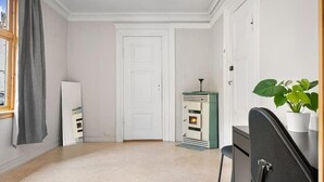 A room with a white door, a small green heater, a chair, and a potted plant. - The Red House - Affordable living (Bergen)