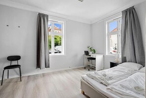 A modern bedroom with a bed, a desk, and a chair. - The Red House - Affordable living (Bergen)